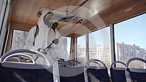 Hazmat team worker disinfects bus seats with antibacterial sanitizer sprayer on coronavirus covid-19 quarantine. Man in