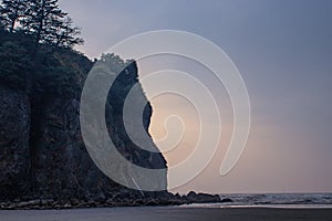 hazy evening with sun behind rock at beach