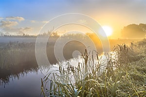 Hazy sunrise over River in dutch countriside