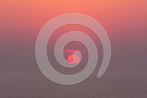 Hazy sunset on the sea with red sun photo