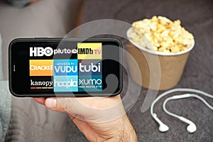 HBO, Pluto TV, IMDb TV, Crackle, Vudu, tubi, kanopy, hoopla, xumo logo on the mobile phone screen with popcorn box and