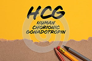HCG human chorionic gonadotropin. Torn cardboard paper on yellow background