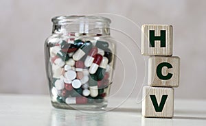 HCV - acronym on cubes on a light background with a capacity with tablets