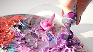 HD. artist squeezes from the tube to the palette purple oily paint.