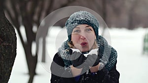 HD Happy young woman holds full plams of snow and blow it out