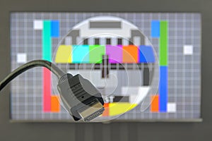 HDMI cable plug in front of tv screen displaying test image