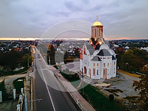 HDR aerial view of old church near river and bridge in small european city at epic sunset