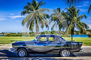 HDR - American black vintage car parked under palms near the beach in Varadero Cuba - Serie Cuba Reportage