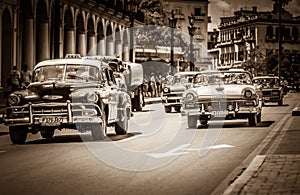 HDR - American Chevrolet classic cars and a Ford Fairlane classic car with white roof drives o
