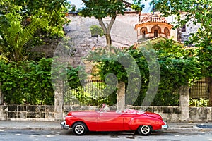 HDR - American red Oldsmobile convertible vintage car parked on the Malecon before a fortress el Morro in Havana Cuba - Serie Cuba