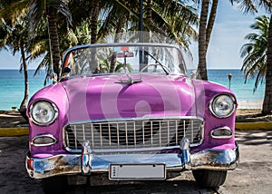 HDR Cuba pink american classic car parked under palms near the beach in Varadero