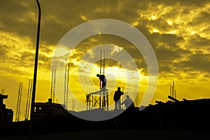 HDR effect of silhouette workers working at building construction side at sunset time