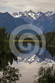 Amazing nature view of calm mountain Lake Matheson, mirror reflection in water reflecting the peaks of Southern Alps, Fox Glacier