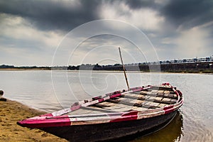 HDR landscape of a boar tied at the corner of river bed sandy beach and cloudy sky day time scene.