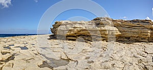 HDR panorama photo of a sunny day at the sea coast with deep blue clean water and a nice stone beach and a large rock on the right