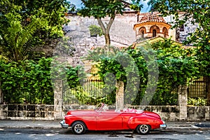 HDR - Red american convertible vintage car parked before the historical fortress el Morro in Havana