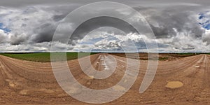 hdri 360 panorama on wet gravel road with puddles among fields in spring nasty day with storm clouds in equirectangular full