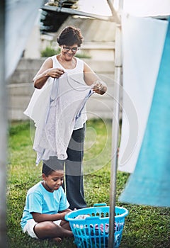 Hea always willing to help with housework. a grandmother and her grandson hanging laundry together outdoors.