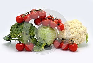 Head of cabbage, inflorescences of broccoli and cauliflower and red ripe tomatoes on a light background.