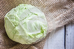 Head of cabbage on sackcloth, white wooden table