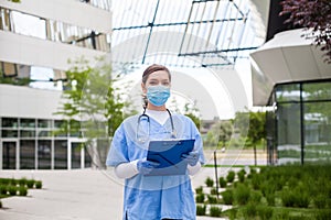 Head of care wearing personal protective equipment holding folder standing in front of nursing home,Coronavirus COVID-19 pandemic