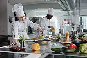 Head chef cooking food for dinner service while adding ingredients to meal.