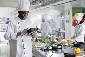 Head chef with modern touchscreen tablet device searching for gourmet cuisine dish recipe