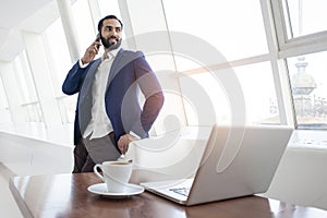 The head of the company stands in a white office and looks out the window, a successful businessman at a working place, an office