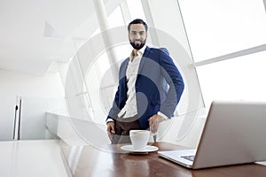 The head of the company stands in a white office and looks out the window, a successful businessman at a working place, an office