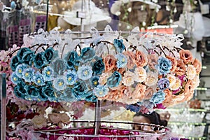 Head crown. Store front hanging on metal shelves. There are fake textile flowers on the crown.