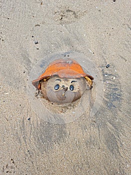 Head of drowned Baby doll on beach sand