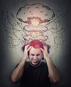 Head explosion metaphor. Bewildered man messing up and pulling his hair,  eyes closed screaming and clenching teeth. Suffering photo
