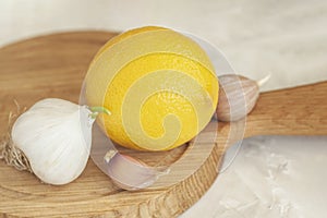 Head of garlic with slices and lemon on wooden cutting board close-up, folk remedies for flu and colds, concept of