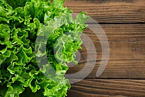Head of green lettuce salad on wooden kitchen table, top view. Copy space for text. Healthy food