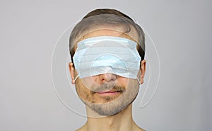 Head of happy smiling man with medical protective mask on his eyes, virtual entertainment during isolation, new normal