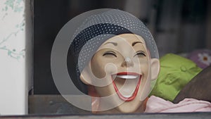 Head of mannequin in store window as laughing woman with her mouth wide open