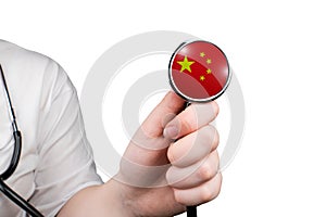 The head of a medical stethoscope in the shape of the Chinese flag in a hand