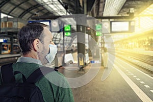 Head portrait of a man in a face blue mask stands on an empty railway platform