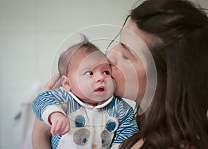 Head portrait of mum kissing her baby newborn