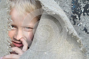 The head portrait of a poor boy. Head in a sackcloth. Emotions.