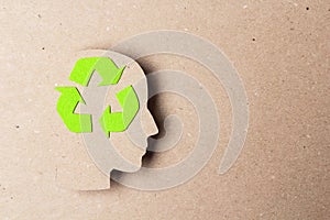Head profile silhouette with recycle symbol on brown paper background. Ecology thinking