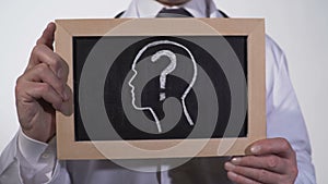 Head with questionmark drawn on blackboard in physician hands, diagnostics