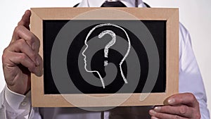 Head with questionmark drawn on blackboard in physician hands, diagnostics