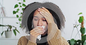 Head shot afro american millennial woman sick girl blows her runny nose into white paper napkin needs doctor sniffles