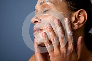 Head shot of beautiful woman with perfectly healthy skin, holding hands on her face, performing smoothing massage, removing makeup