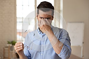 Employee suffering from dry eyes syndrome or eyestrain. photo