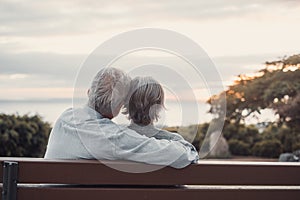 Head shot close up portrait happy grey haired middle aged woman with older husband, enjoying sitting on bench at park. Bonding