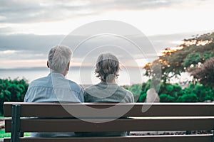 Head shot close up portrait happy grey haired middle aged woman with older husband, enjoying sitting on bench at park. Bonding