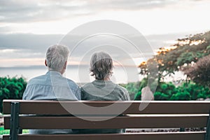 Head shot close up portrait happy grey haired middle aged woman with older husband, enjoying sitting on bench at park. Bonding