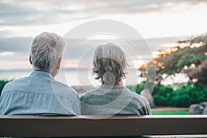 Head shot close up portrait happy grey haired middle aged woman with older husband, enjoying sitting on bench at park. Bonding